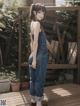 A woman in overalls standing on a wooden deck.