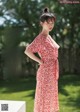 A woman in a red and white dress standing in a park.