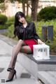 A woman in a black shirt and red skirt sitting on a ledge.