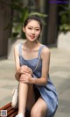 A woman in a blue dress sitting on a bench.