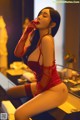 A woman in a red lingerie sitting on a bed.