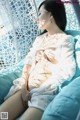 A woman in a white shirt is sitting on a blue chair.