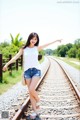 A woman standing on a train track with her arms outstretched.