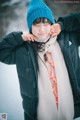 A woman wearing a blue hat and scarf in the snow.