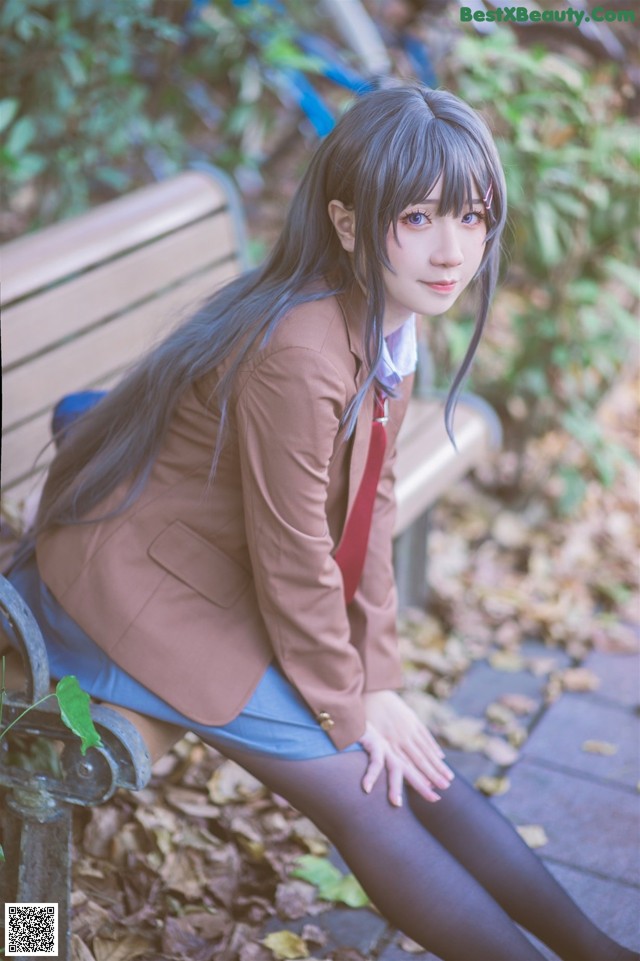 A woman sitting on a bench in a park.