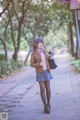 A woman in a school uniform is walking down a sidewalk.