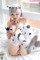 A woman in a cow costume sitting on a bed.