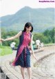 A woman in a pink and blue dress is walking down the street.