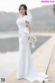 A woman in a white wedding dress holding a bouquet of flowers.