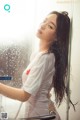 A woman in a white shirt is standing in a shower.