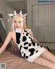 A woman in a cow costume sitting on a bed.