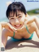 A woman in a blue bikini laying on the beach.