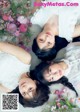 A group of three young women laying on top of a bed of flowers.