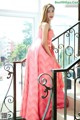 A woman in a pink dress standing on a balcony.