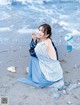 A woman sitting on a rock on the beach.