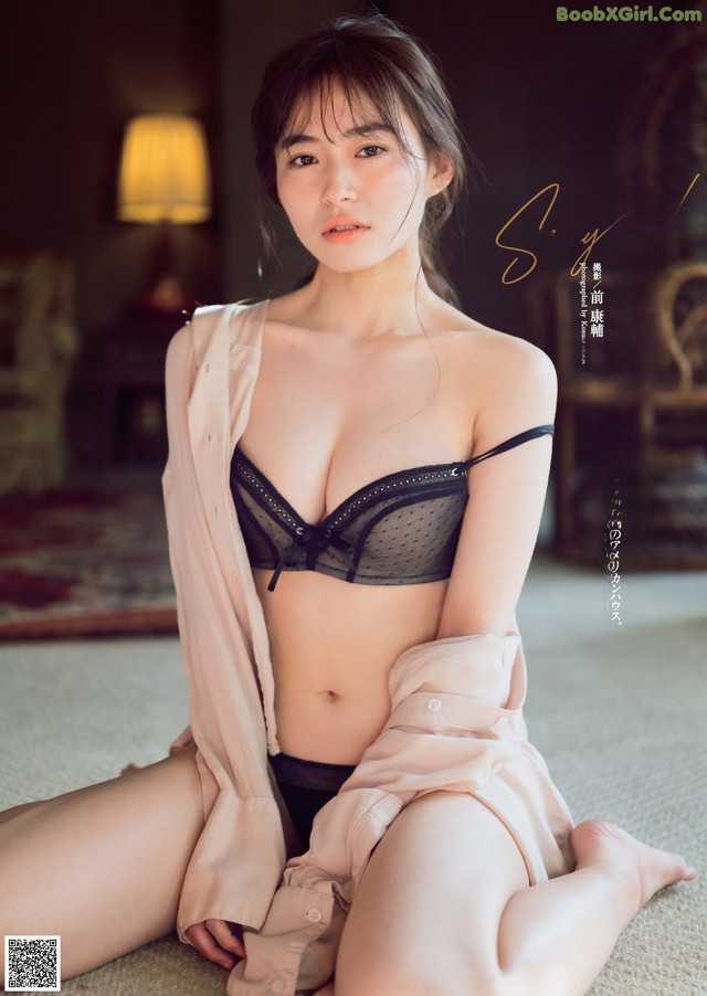 A woman sitting on the floor wearing a black bra and panties.